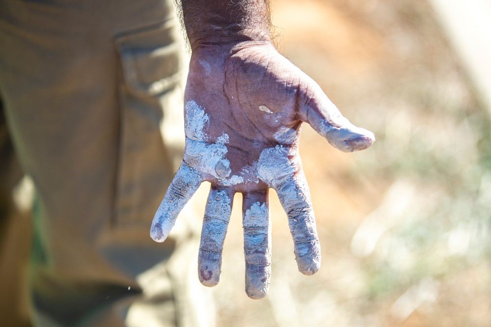 An Aboriginal man's hand is covered in white ochre paint