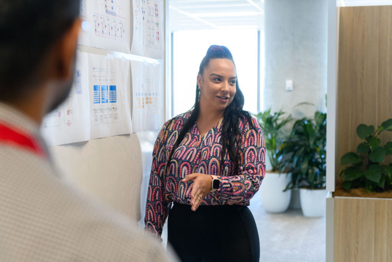 A woman stands at a whiteboard presenting