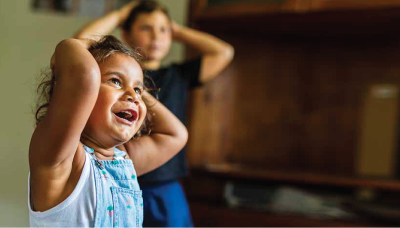 Aboriginal child smiling with hands on head