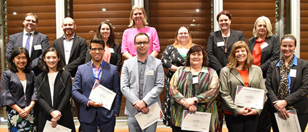 2 rows of people standing looking to camera holding certificates