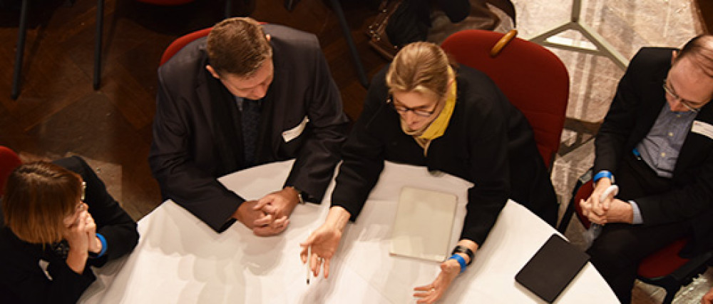 A group of people sit at a circular table in discussion