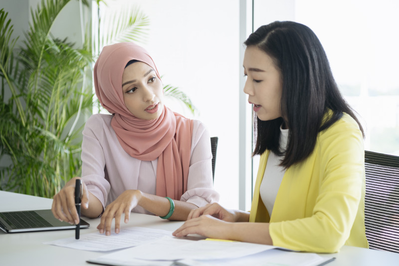 Two women have a discussion with papers in front of them