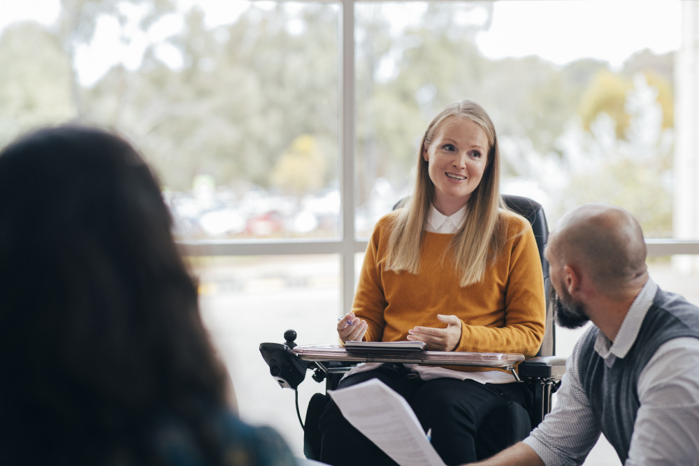 woman in wheelchair talking to a male colleague