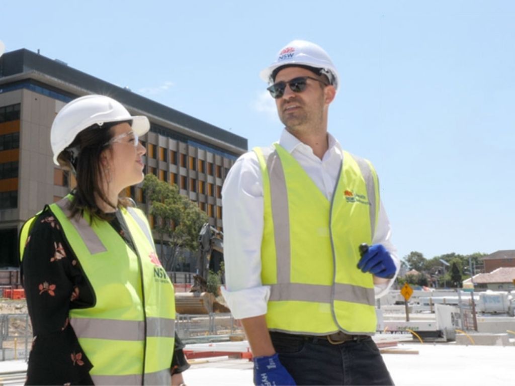 Woman and man wearing high visibility clothing and hard hats on a construction site