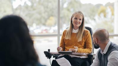 woman in wheelchair talking to a male colleague